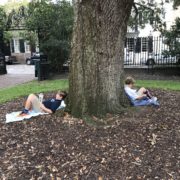 students lean against a tree and read