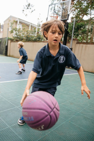 boy dribbling basketball outside