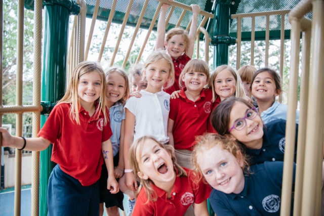 girl students pose and smile on play structure