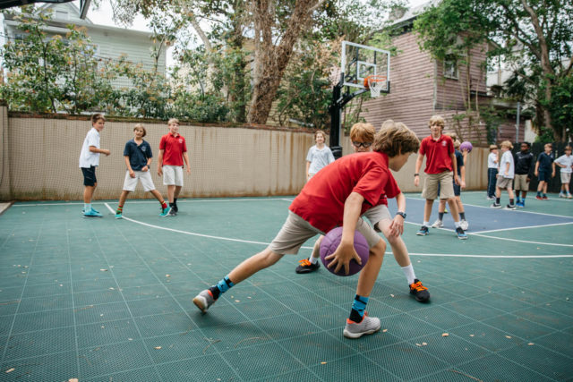 boy students play basketball outside recess