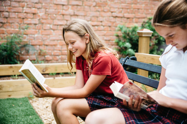 students read and smile outside in garden