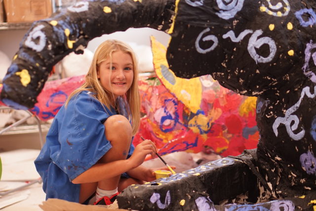 student smiles while painting project