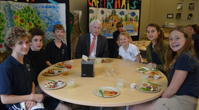 students eat lunch with school head around table