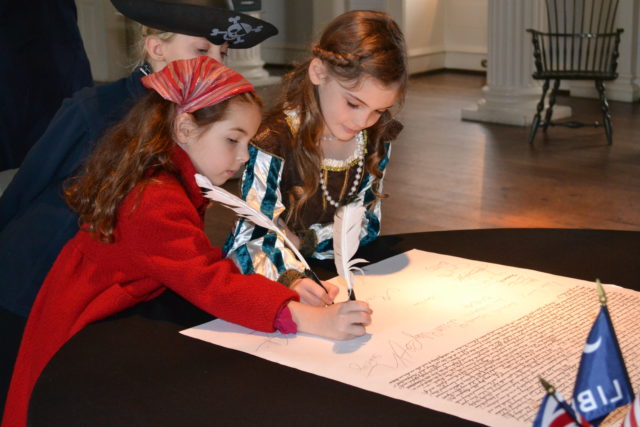 two girls in costume signing a document