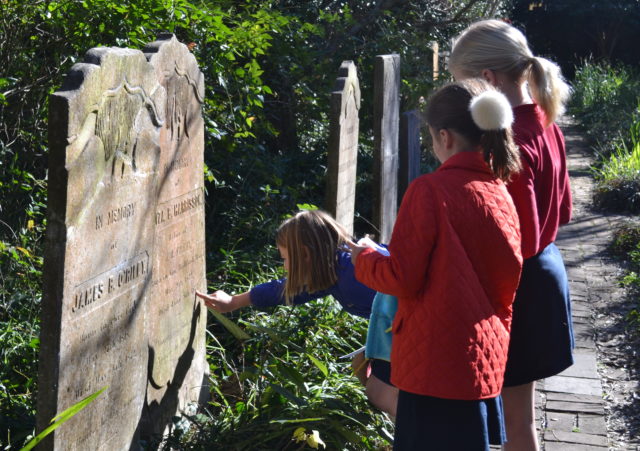students inspect headstone in cemetary