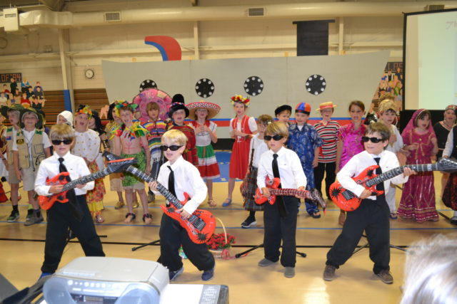 four 2nd graders with guitars perform around the world