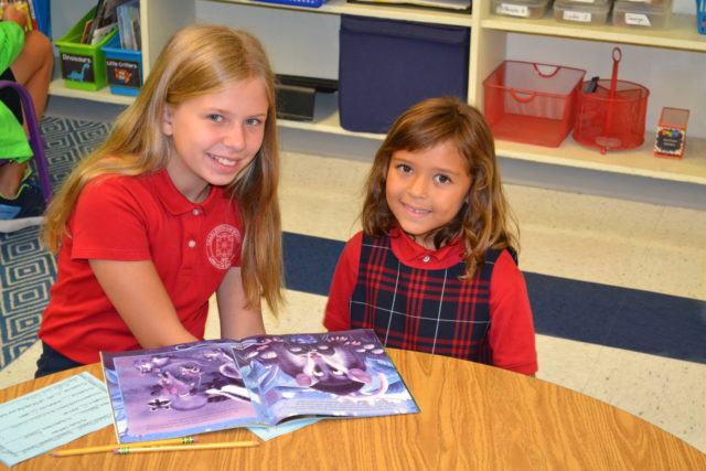 big and little students reading together