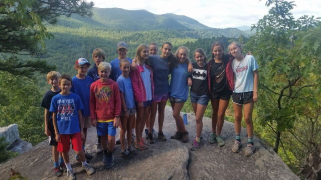 students hiking eagle rock pose for scenic picture