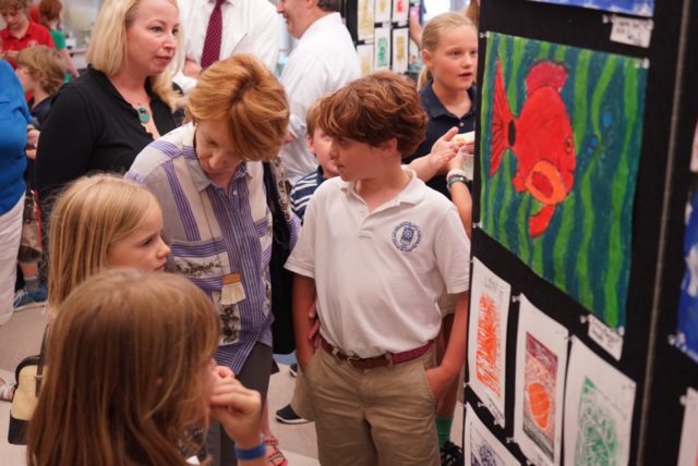 a student shows his painting of a red fish at student art show